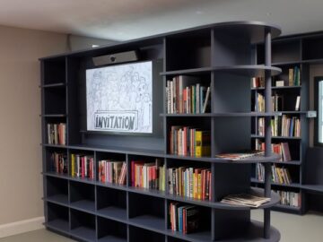 The Create reading room - navy bookshelves with a blue floor. A TV shows an archival black and white image