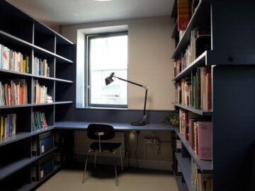 The Create reading room - navy bookshelves with a blue floor. A desk is featured, with a black lamp.