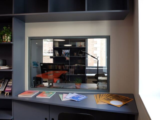 The Create reading room, featuring navy bookshelves and a window looking into the archival room