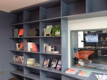 The Create reading room, featuring navy bookshelves and a window looking into the archival room
